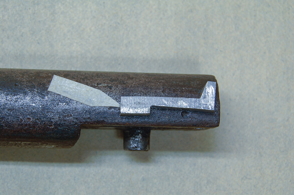 A new extractor lying on the barrel shows its exact shape. The surface on the lower front (see arrow) limits the amount of breechblock that swings open.